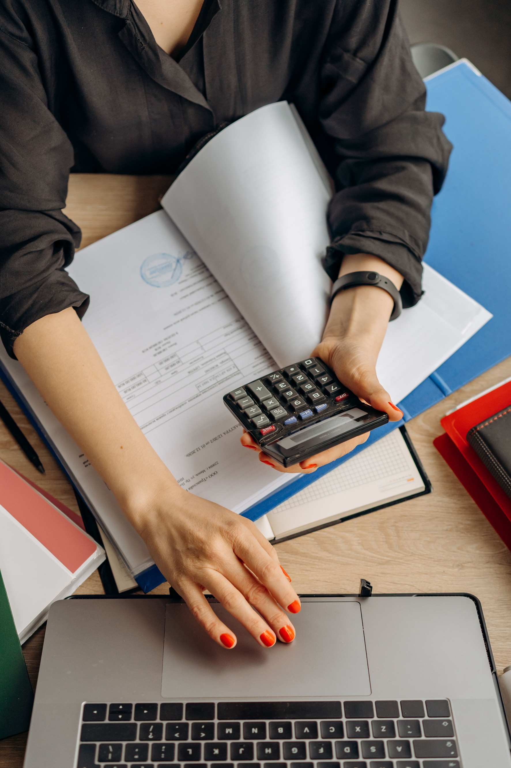 Nahaufnahme eines Laptops mit Tabellenkalkulation, Dokumente und Taschenrechner auf dem Schreibtisch
